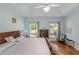 Serene main bedroom with light blue walls, tray ceiling, hardwood floors, and two windows with views of the yard at 1605 Little Lisa Ln, Snellville, GA 30078