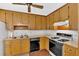 Galley kitchen with wooden cabinets, a double basin stainless steel sink, and a black stove at 4807 Willowwood Ne Dr, Kennesaw, GA 30144
