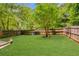 Spacious backyard is fully fenced and features a lush green lawn and some small trees at 5850 Shannon Dr, Cumming, GA 30040