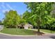Charming home with manicured lawn, mature trees and a well-lit driveway on a sunny day at 5850 Shannon Dr, Cumming, GA 30040