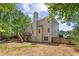 Backyard view showing a multi-story home with deck, stairs, lush landscaping, and wooded backdrop at 84 Conner Glenn Dr, Hiram, GA 30141