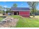 A side view of a two-story barn with black metal roof sits atop a grassy hill at 1646 Highway 92 N, Fayetteville, GA 30214