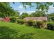 Lush green back yard featuring trees, shrubs, and a deck with outdoor furniture at 1932 Brenda Dr, Austell, GA 30168