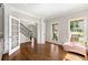 Living room features hardwood floors, multiple windows, and open staircase and doorway at 5652 Harbormist Dr, Powder Springs, GA 30127