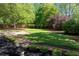 Well-manicured backyard featuring a mix of grass and mulch, framed by mature trees and greenery at 4915 Bayberry Dr, Cumming, GA 30040