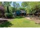 Expansive backyard view of the home with a screened-in porch, manicured lawn, and mature trees at 4915 Bayberry Dr, Cumming, GA 30040