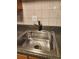 Stainless steel kitchen sink with grid and modern faucet against a tiled backsplash at 1502 Countryside Se Pl # 1502, Smyrna, GA 30080