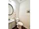 Powder bathroom featuring a pedestal sink, toilet, framed mirror and wood floors at 3981 Isaac Ct, Lilburn, GA 30047