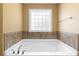 A soaking tub with tile surround sits beneath a window allowing for natural light at 114 Brookstone Dr, Carrollton, GA 30116