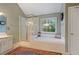 Bright bathroom features separate shower and tub next to a large window overlooking trees at 1360 Woodvine Way, Alpharetta, GA 30005