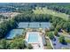 An aerial shot of tennis courts and a community pool surrounded by trees, with a golf course in the background at 2118 Town Manor Ct, Dacula, GA 30019