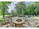 Inviting backyard features a cozy fire pit, in-ground pool with waterfall, brick paved patio and green trees at 2118 Town Manor Ct, Dacula, GA 30019