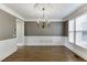 Formal dining room with wainscoting, hardwood floors, decorative chandelier, and large sunlit windows at 2118 Town Manor Ct, Dacula, GA 30019