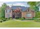 Beautiful two-story brick home featuring manicured landscaping and mature trees surrounding the property at 2118 Town Manor Ct, Dacula, GA 30019