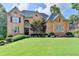 Elegant brick home featuring manicured lawn, mature trees, and a welcoming entrance at 2118 Town Manor Ct, Dacula, GA 30019