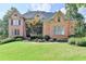 Elegant brick home featuring manicured lawn, mature trees, and a welcoming entrance at 2118 Town Manor Ct, Dacula, GA 30019