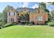 Elegant brick home featuring manicured lawn, mature trees, and a welcoming entrance at 2118 Town Manor Ct, Dacula, GA 30019