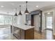 Bright kitchen features a large island with white countertop, dark cabinets, and modern pendant lighting at 2118 Town Manor Ct, Dacula, GA 30019