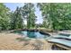 Luxury backyard oasis with a stunning pool, stone patio, lounge chairs, and lush landscaping at 2118 Town Manor Ct, Dacula, GA 30019