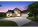 Stately brick home at dusk with a circular driveway, lush lawn, mature landscaping, and a three-car garage at 9325 Saint Georgen Cmn, Duluth, GA 30097