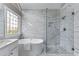 Luxurious bathroom featuring a soaking tub, a glass-enclosed shower, and marble tile at 4648 Glenshire Pl, Atlanta, GA 30338