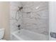 Modern bathtub featuring elegant, light marble-patterned tile surround, a brushed nickel showerhead and faucet at 4648 Glenshire Pl, Atlanta, GA 30338
