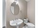 A compact powder room featuring a pedestal sink, an oval mirror, and neutral decor at 4648 Glenshire Pl, Atlanta, GA 30338