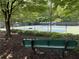 A well-maintained tennis court, enclosed with fencing and seating, is set in a serene, wooded environment at 4648 Glenshire Pl, Atlanta, GA 30338
