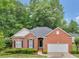 A brick home featuring an attached two-car garage, manicured shrubs, and a well-maintained lawn at 361 Brackin Trce, Grayson, GA 30017