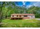Ranch-style home featuring a red roof, brick foundation, and a wooden deck overlooking the grassy front yard at 428 Cornish Mountain Rd, Oxford, GA 30054