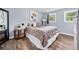 Comfortable bedroom with wood floors, soft lighting, large bed, side table and a window overlooking the greenery outside at 115 S Meadowcliff Cir, Carrollton, GA 30116