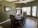 Elegant dining room features stylish chandelier, dark wood table set for six, and natural light from large windows at 1291 Long Acre Dr, Loganville, GA 30052