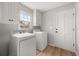 Bright laundry room with appliances, cabinets, wood-look floors, and access door at 5659 Brookstone Nw Dr, Acworth, GA 30101