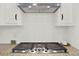 Modern gas cooktop with granite countertops and white tile backsplash underneath a stainless steel vent at 6218 Old Stilesboro Nw Rd, Acworth, GA 30101