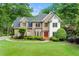 Brick facade home with red doors, manicured lawn and mature trees create a welcoming curb appeal at 125 Forrest Lake Rd, Johns Creek, GA 30022