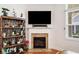Close up of fireplace with decorative mantle and wooden bookshelf next to a window at 306 Cherokee Station Cir, Woodstock, GA 30188