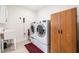 Bright laundry room with washer, dryer, utility sink and wooden storage cabinet at 306 Cherokee Station Cir, Woodstock, GA 30188