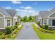 Picturesque street view lined with well-maintained townhomes, manicured lawns, and lush landscaping under a bright sky at 306 Cherokee Station Cir, Woodstock, GA 30188