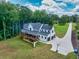 Aerial view of a modern farmhouse with expansive backyard, deck, three-car garage, and lush landscaping at 3180 Lee Dr, Buford, GA 30518