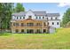 Large backyard with a two-story home featuring a covered patio on both levels and lush trees at 3180 Lee Dr, Buford, GA 30518