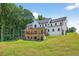 Expansive backyard with a two-story home, featuring a covered patio and lush trees at 3180 Lee Dr, Buford, GA 30518