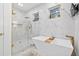 Bright bathroom featuring a freestanding tub, glass-enclosed shower, marble accents, and modern fixtures at 3180 Lee Dr, Buford, GA 30518