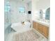 Bright bathroom featuring marble walls, a soaking tub, and double vanities with gold accents at 3180 Lee Dr, Buford, GA 30518