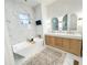 Spa bathroom with sleek tub, custom dual vanities and marble styled tile at 3180 Lee Dr, Buford, GA 30518