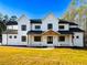 Stunning two-story white farmhouse with black roof, inviting entrance, and lush green lawn at 3180 Lee Dr, Buford, GA 30518
