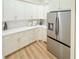 Modern kitchen featuring white cabinets, quartz countertops, stainless steel refrigerator, and light wood floors at 3180 Lee Dr, Buford, GA 30518