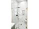 Shower with frameless glass enclosure, marble tiling, brushed gold hardware, and built-in shower niche at 3180 Lee Dr, Buford, GA 30518