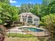 Beautiful backyard with a large pool, spa, and iron fence surrounded by lush landscaping at 8170 Hurakan Creek Xing, Cumming, GA 30028