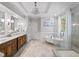 Bright bathroom showcasing double vanities, a glass-enclosed shower, and a soaking tub by the window at 8170 Hurakan Creek Xing, Cumming, GA 30028