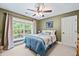 A well lit bedroom features a ceiling fan, window overlooking the yard, and neutral carpet at 8170 Hurakan Creek Xing, Cumming, GA 30028